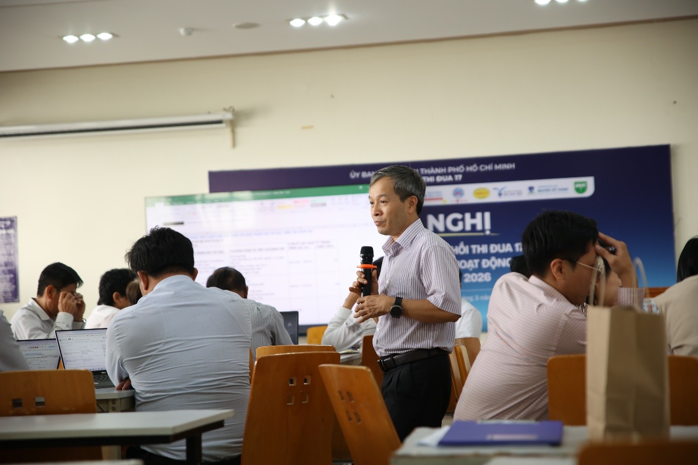 A person holding a microphone in front of a group of peopleAI-generated content may be incorrect.